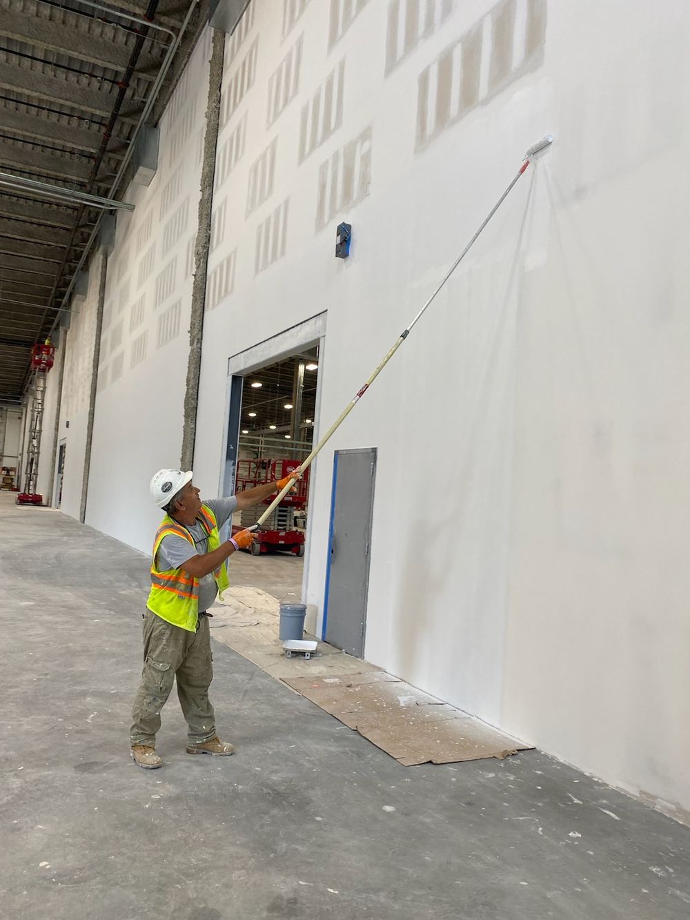 JP Standard crew member painting a warehouse wall at Amazon DYY3